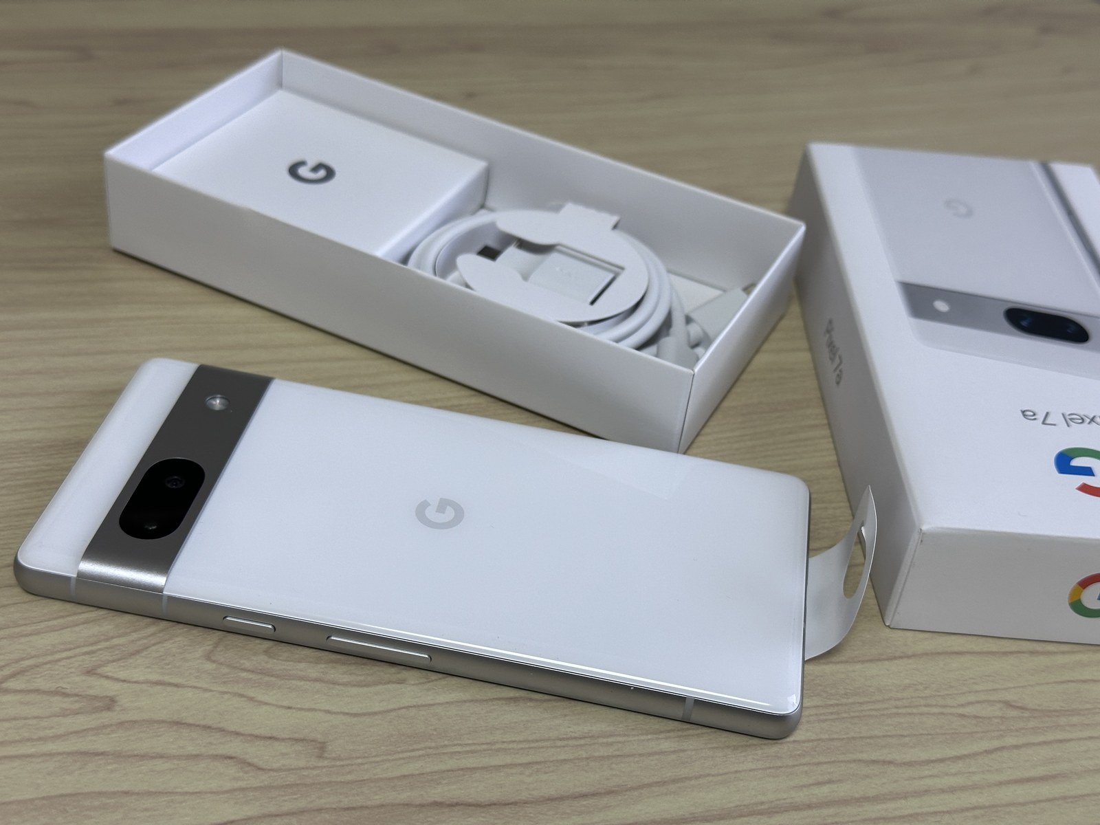 Google Pixel 7a obok otwartego pudełka i przewodu