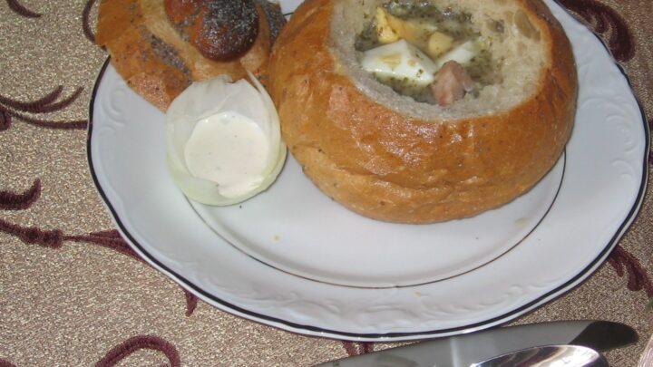 Żurek podany w wydrążonym pieczywie z dodatkami na talerzu