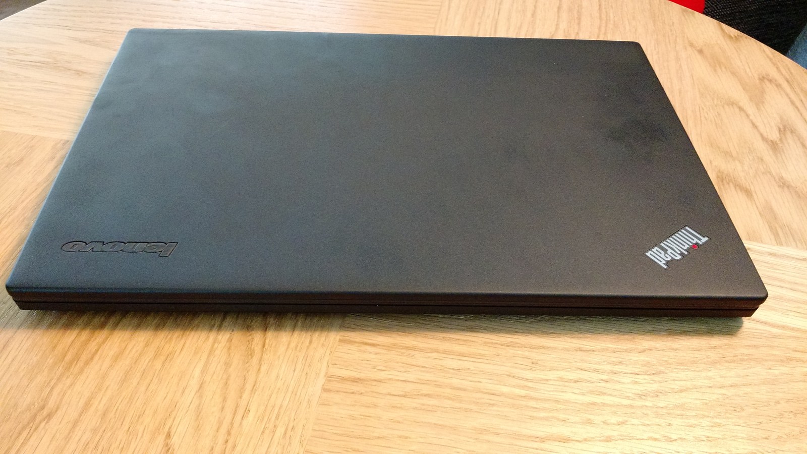 Zamknięty laptop Lenovo ThinkPad X240 leżący na powierzchni, fotografia archiwalna.