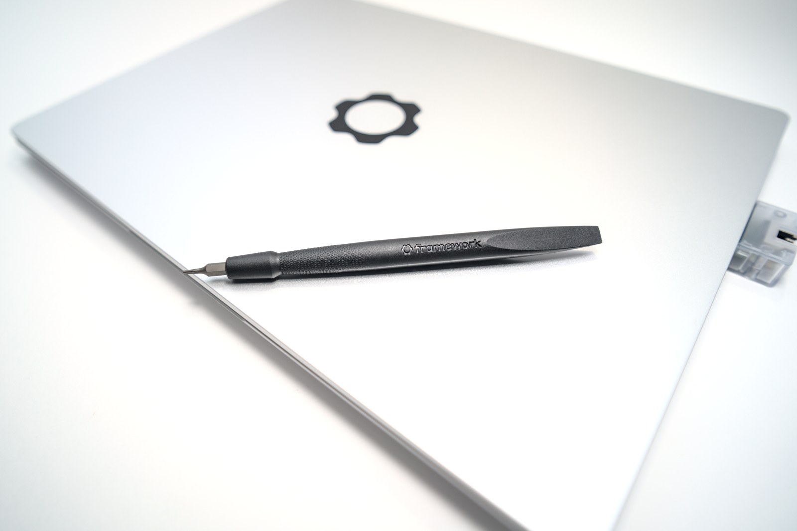 Zamknięty laptop Framework 13 AMD z narzędziem i modułem Ethernet.