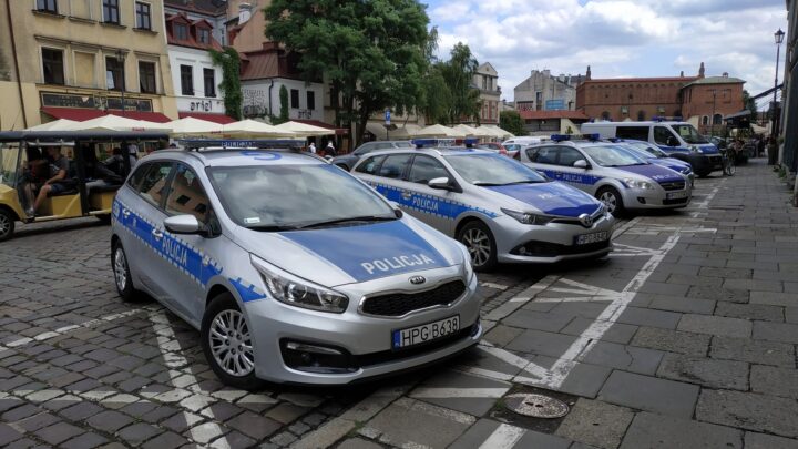 Oznakowane samochody polskiej policji zaparkowane na ulicy w Krakowie.