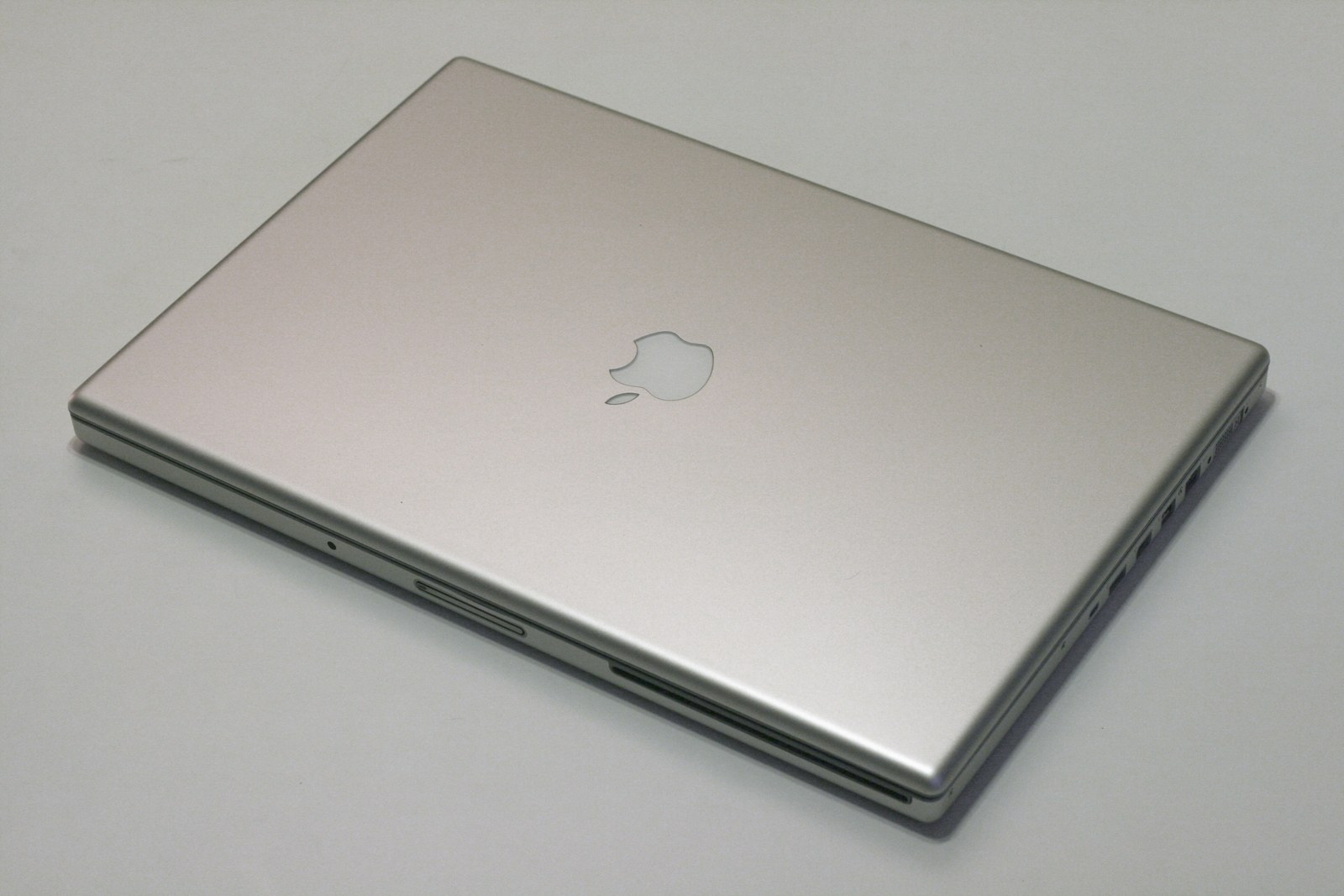 Zamknięty srebrny MacBook Pro na jasnym stole.