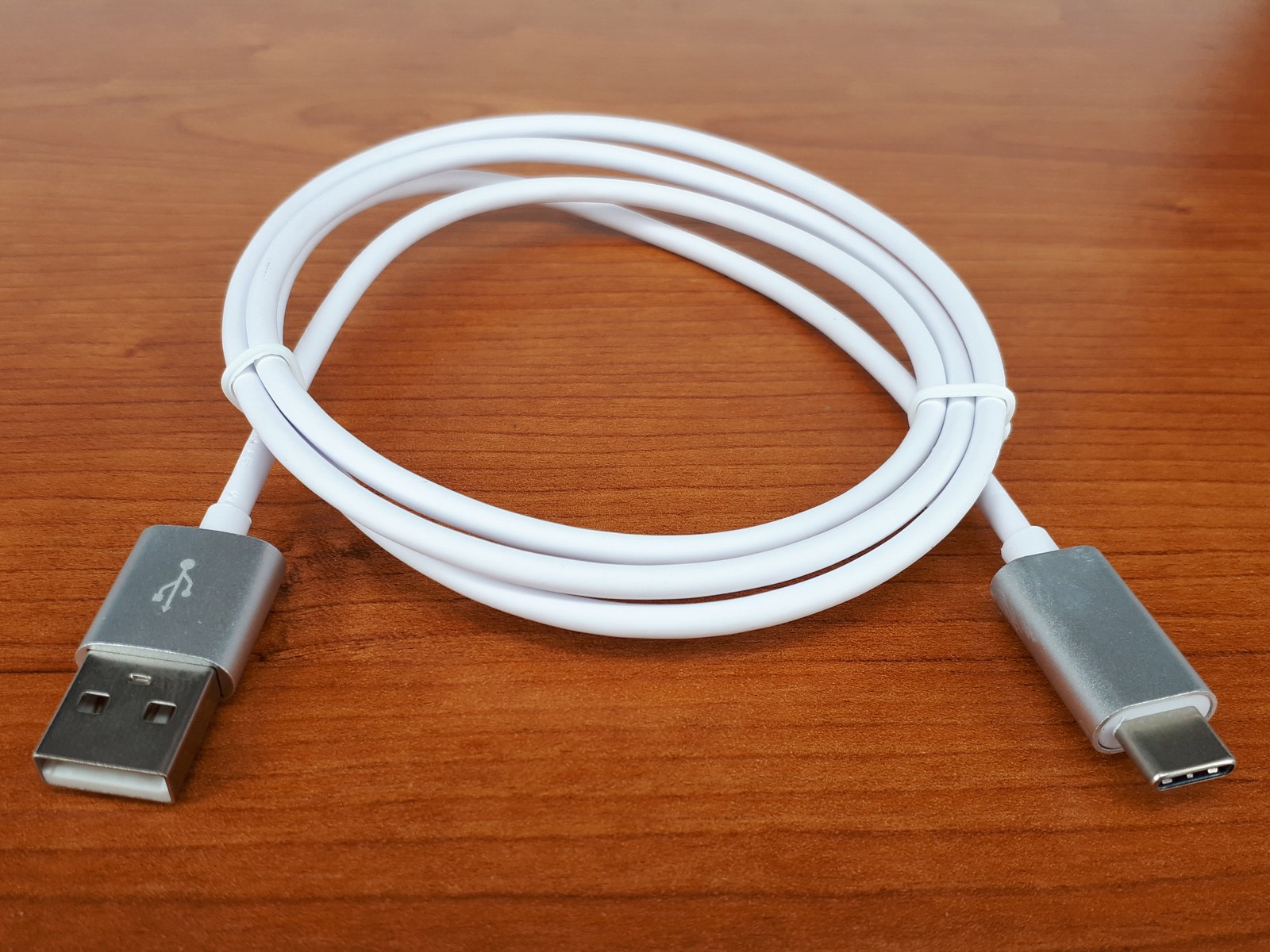 Biały kabel ze złączami USB-A i USB-C na drewnianym blacie