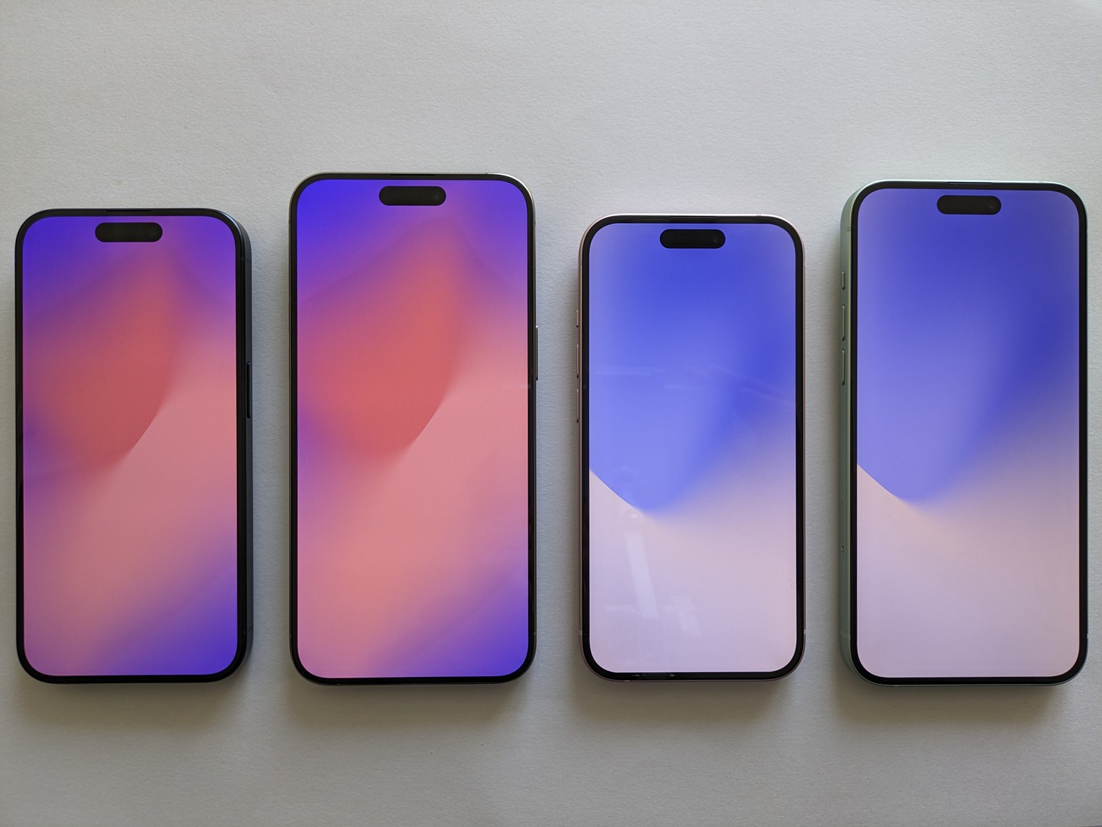 Cztery iPhone'y ułożone obok siebie z kolorowymi ekranami