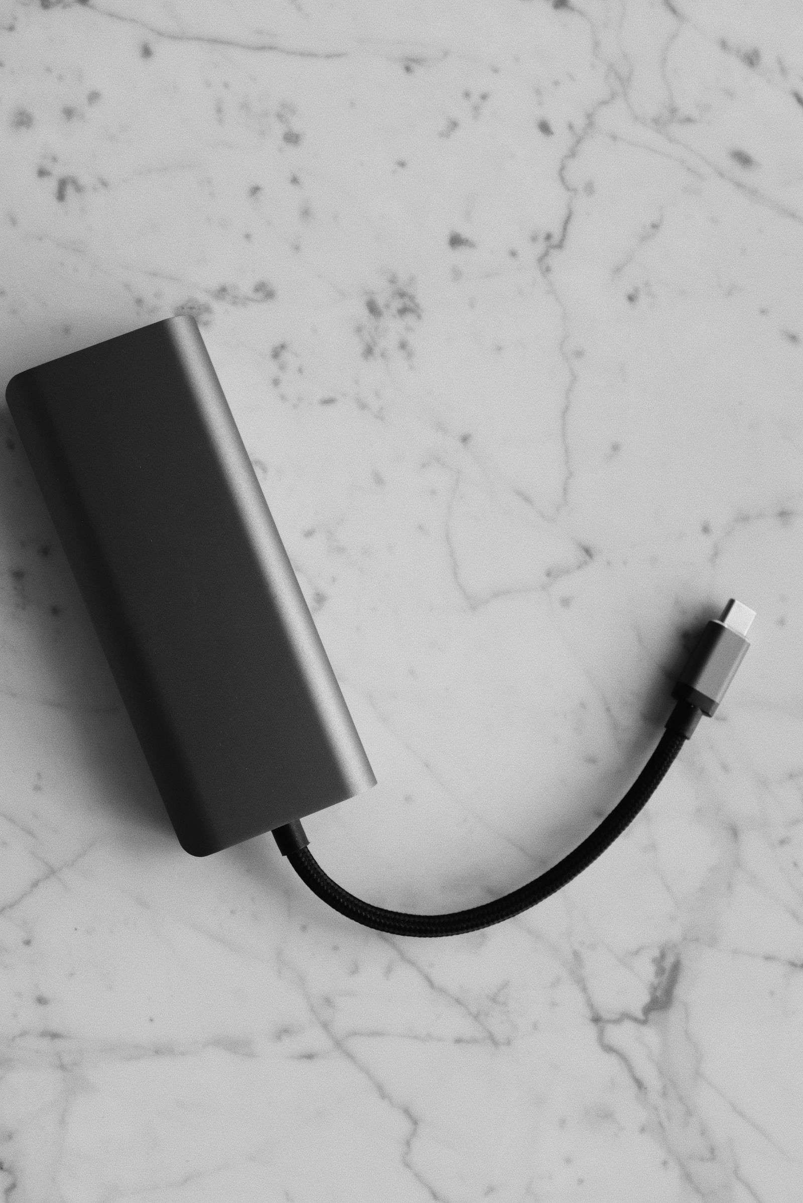 Powerbank z przewodem na jasnym blacie, zdjęcie ilustracyjne.