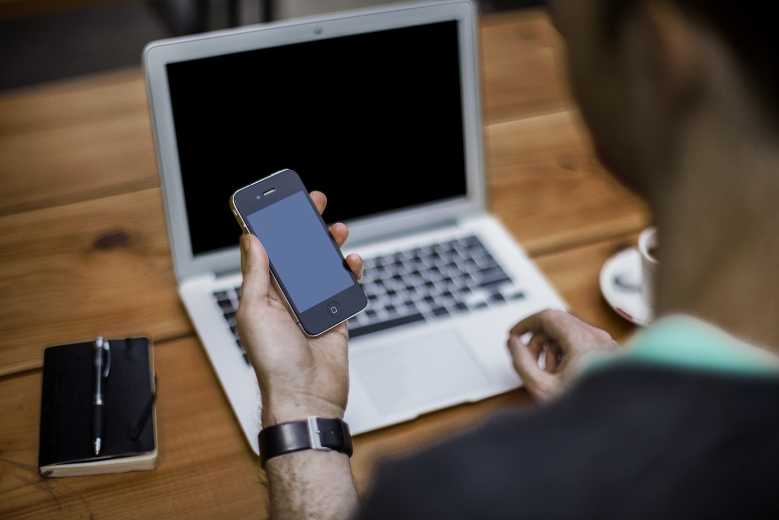 Telefon trzymany obok otwartego laptopa