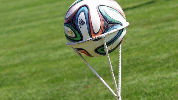 Piłka futbolowa Adidas Brazuca na tle murawy