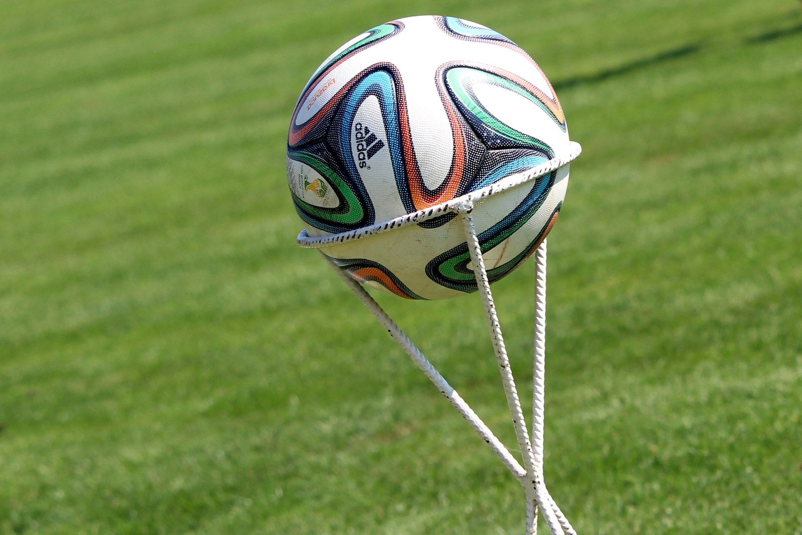 Piłka futbolowa Adidas Brazuca na tle murawy