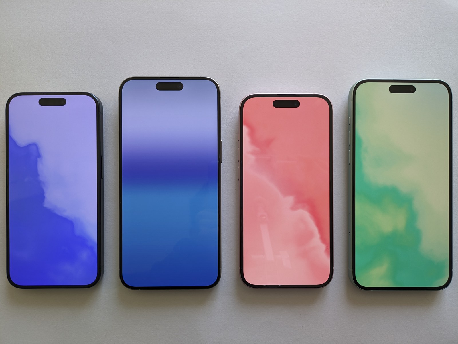 Cztery iPhone’y z ekranami przedstawiającymi kolorowe gradienty