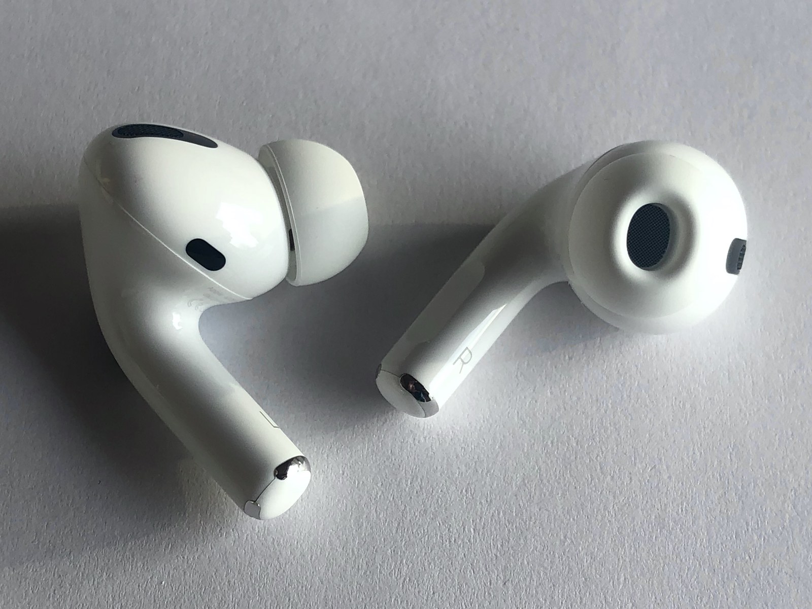 Białe słuchawki AirPods Pro leżące na jasnym podłożu